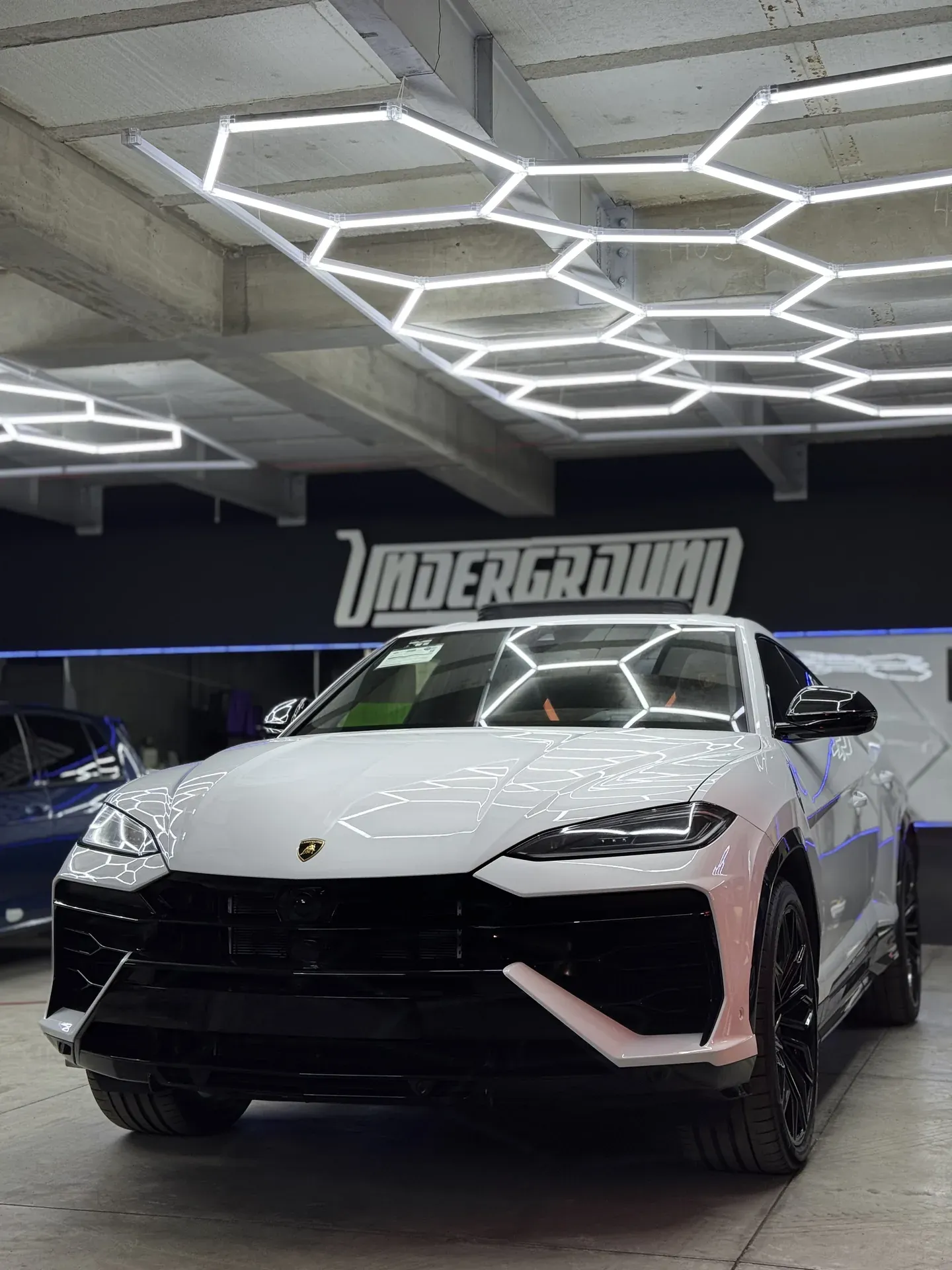Lamborghini Urus blanca bajo las luces LED hexagonales del taller UNDERGROUND