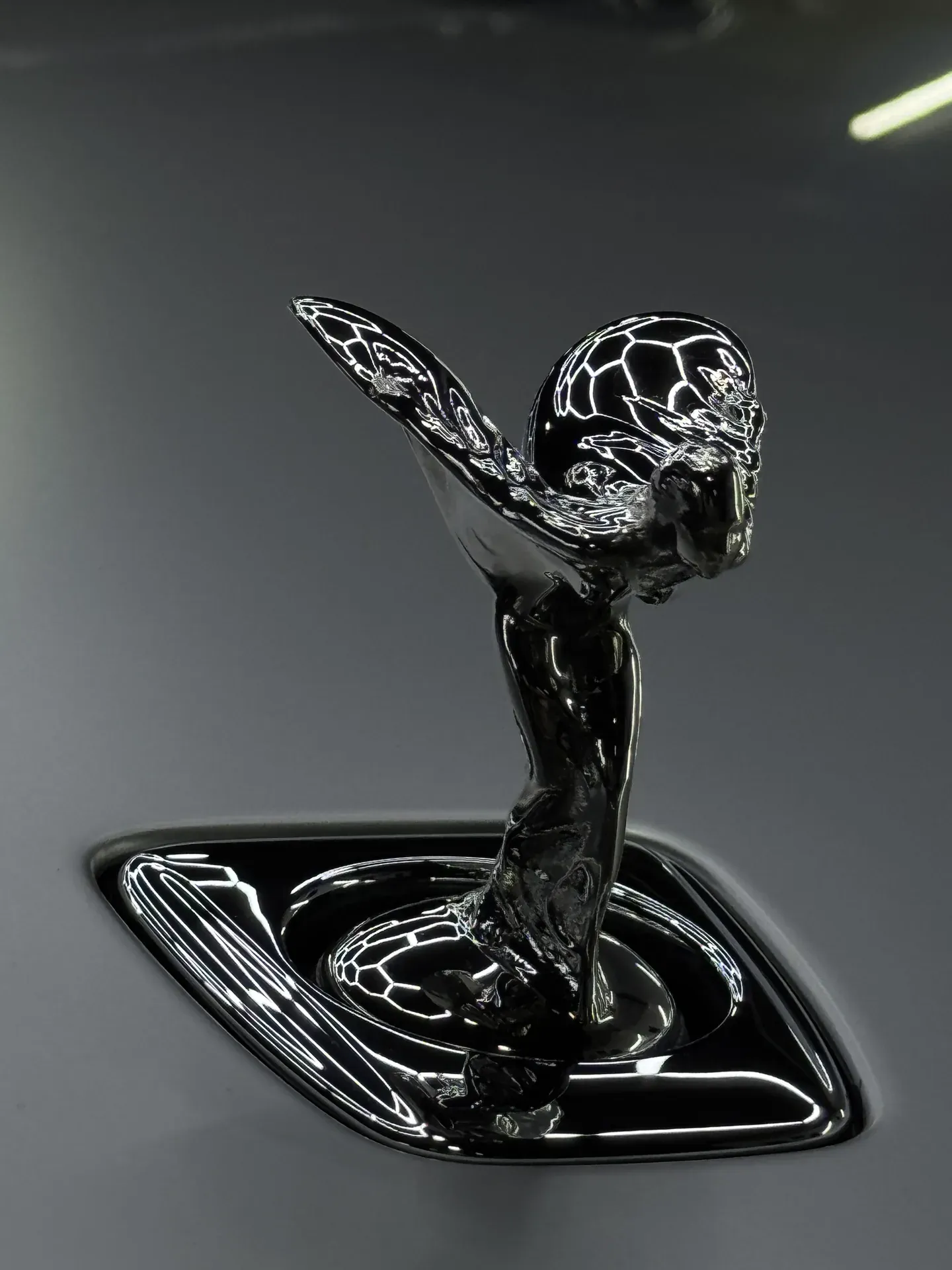 Espíritu del Éxtasis de un Rolls-Royce en cromo negro pulido, reflejando sin distorsión